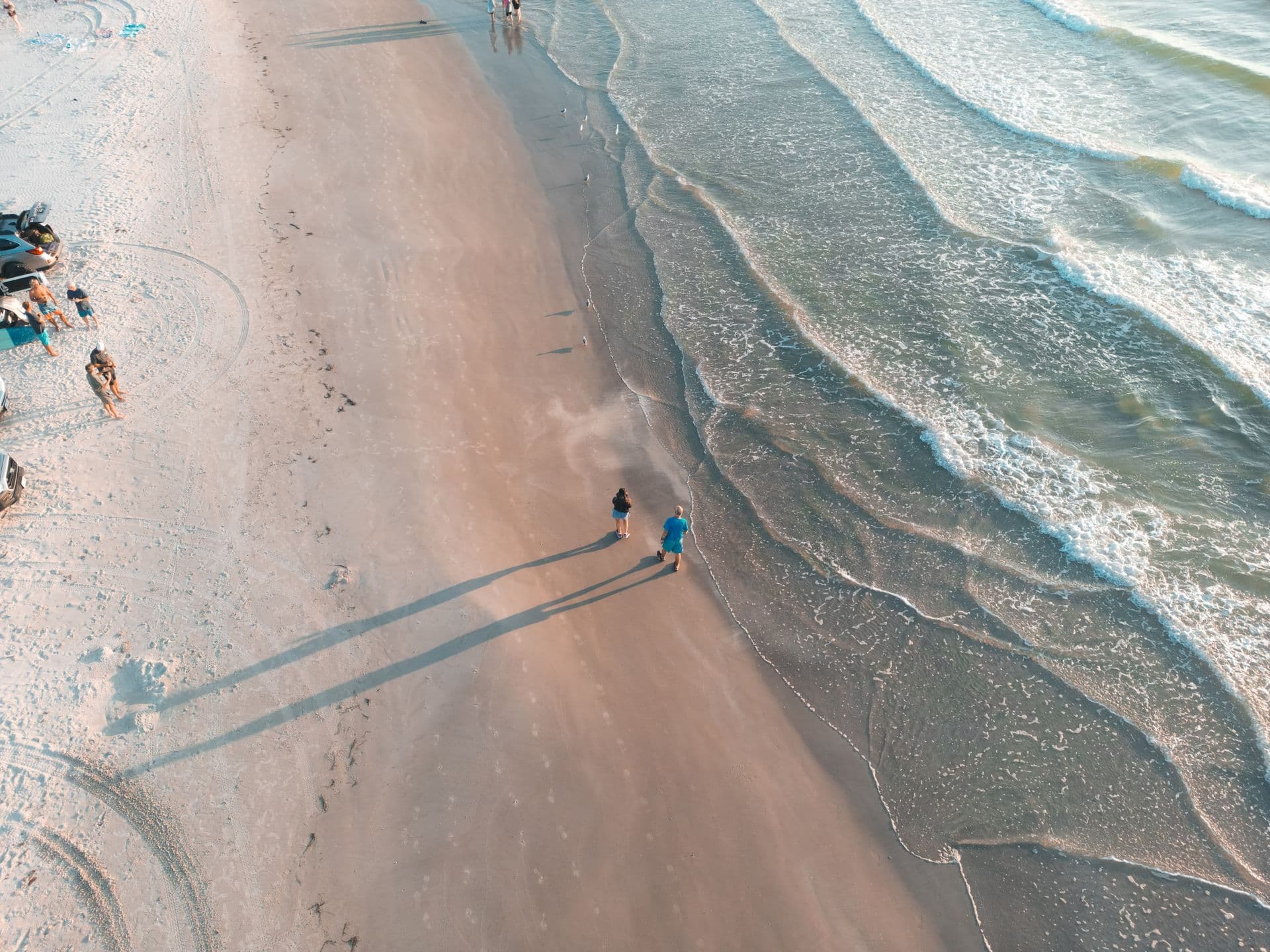 Aerial view of people walking along a Gulf beach at the waterline